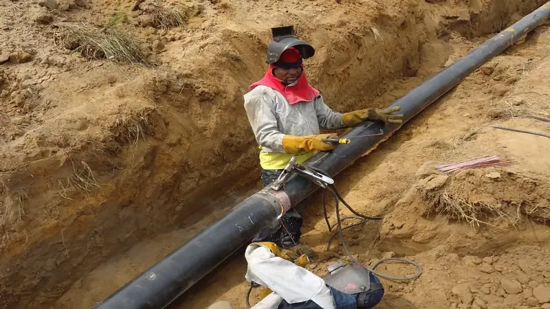Buried pipeline section being coated and wrapped in an open trench during sectional replacement